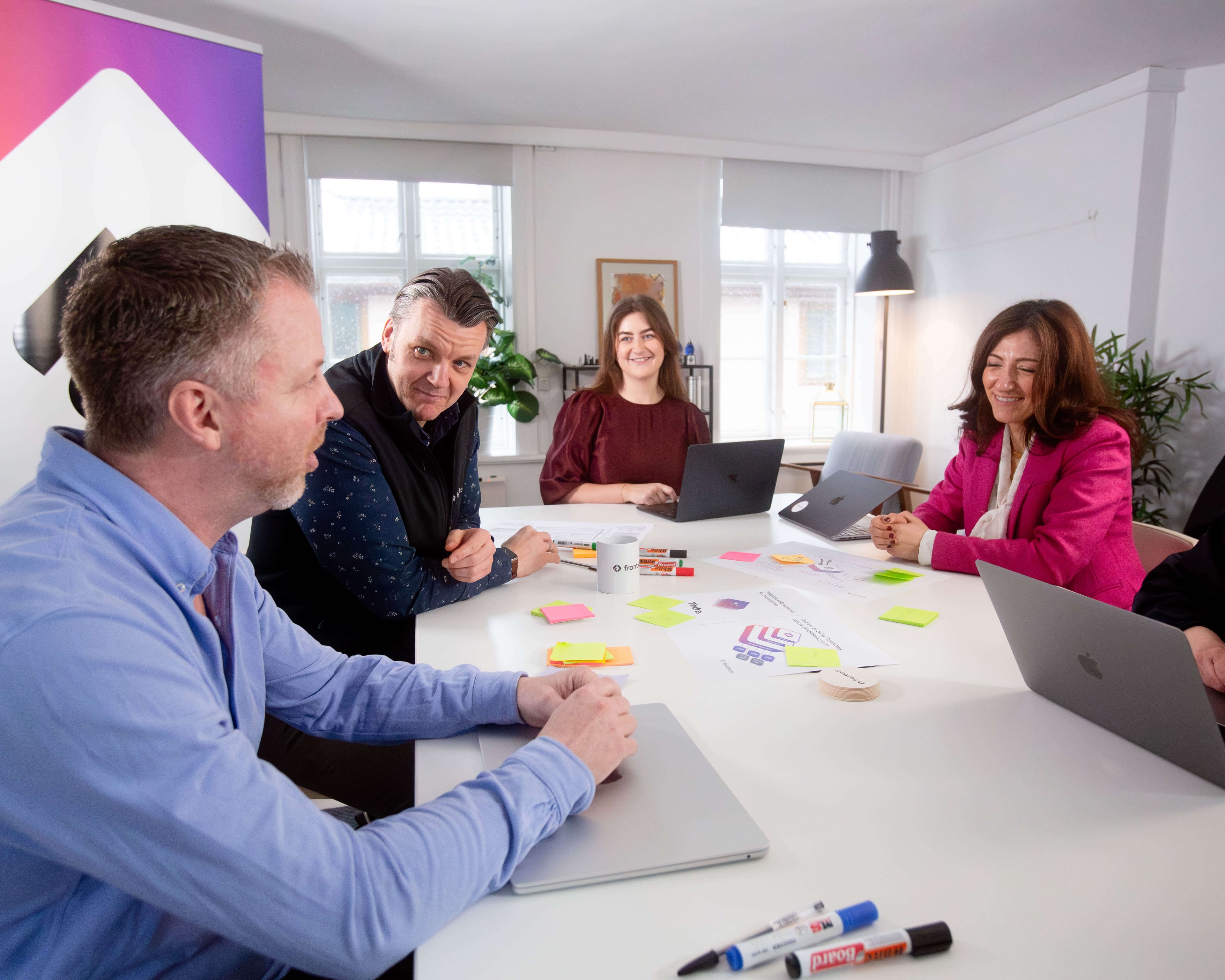 Frontkom-teamet i et møte rundt et bord med post-it lapper og laptops